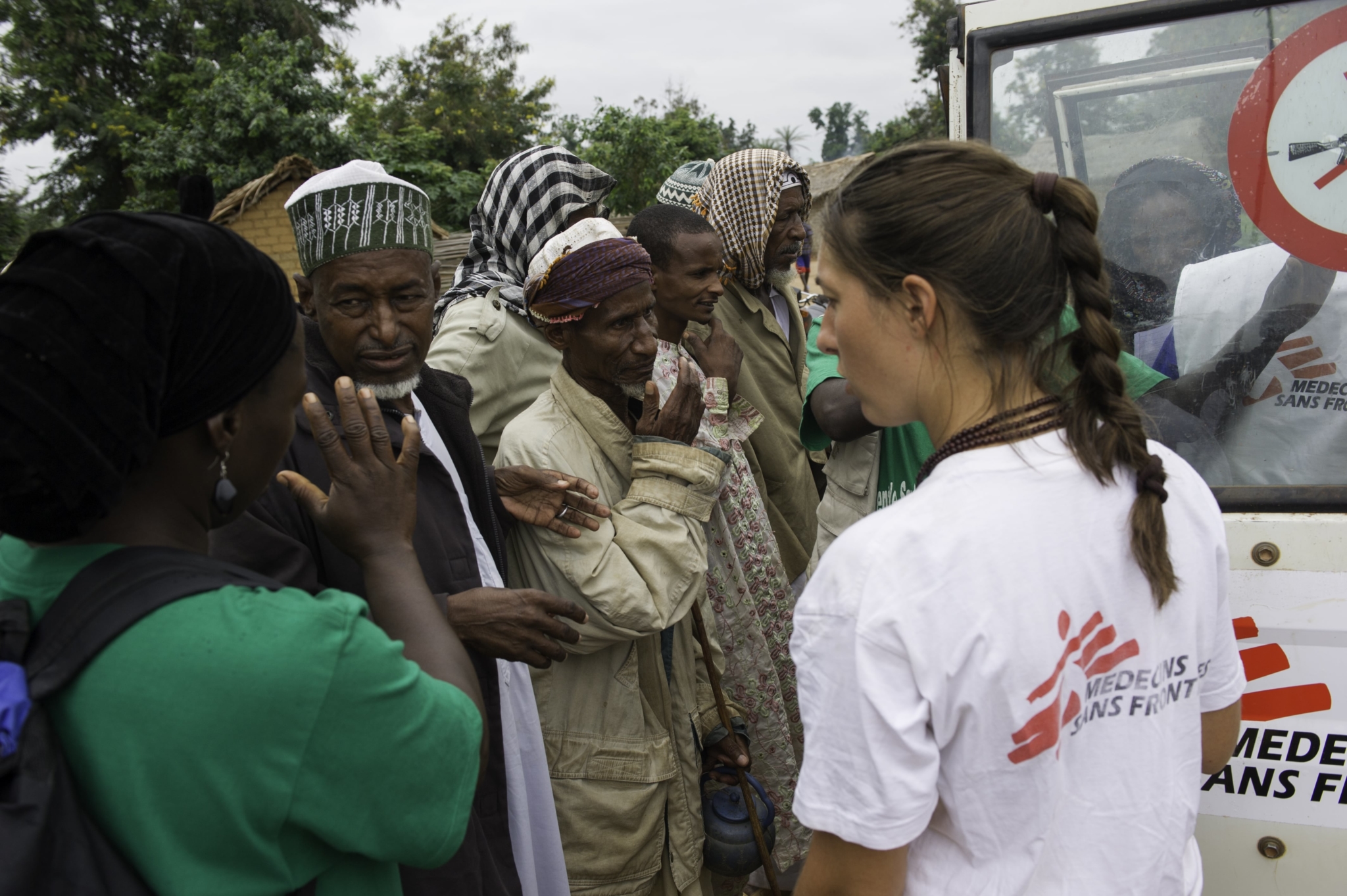 Katrin Jullien, coordenadora de projeto de MSF, e um agente de saúde local informam ao homem que testou positivo para a doença do sono sobre a necessidade de ir ao hospital realizar um segundo teste.