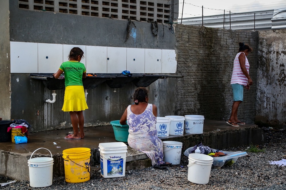 Mulheres lavam roupas com água trazida em baldes no abrigo indígena de Pintolândia, em Boa Vista. O abrigo tem poucos lugares onde as pessoas podem pegar água.