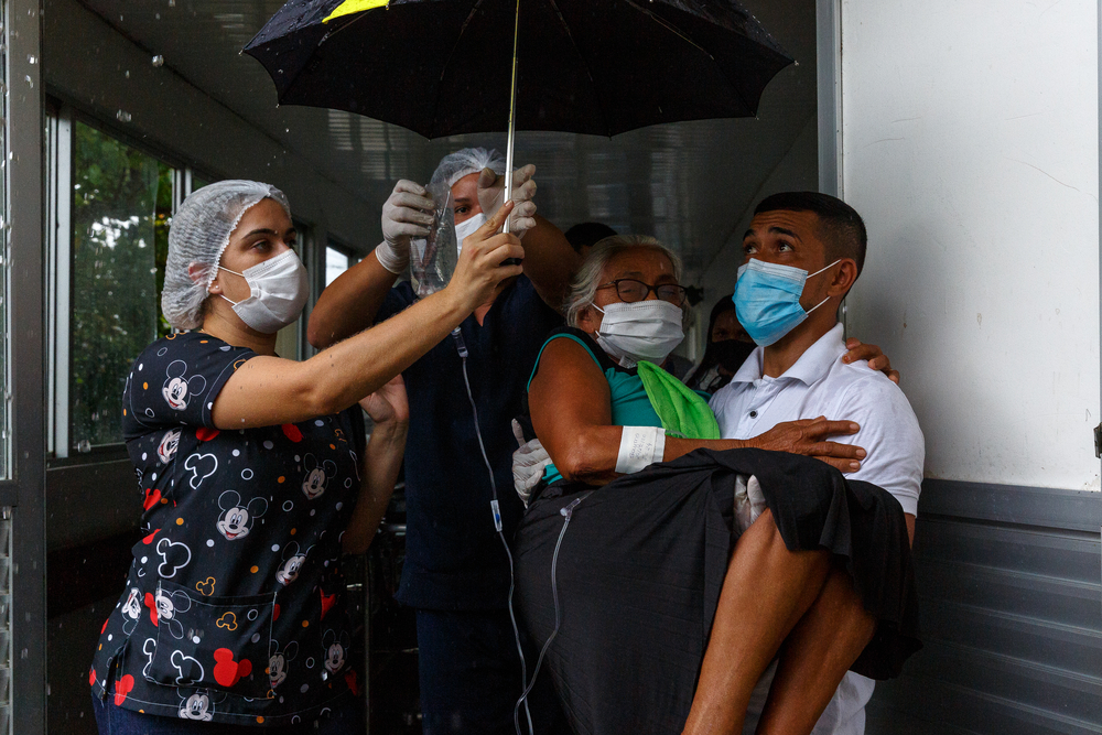 Uma mulher com COVID-19 é levada a uma ambulância, que a levará ao aeroporto para depois ser transferida para Manaus, a capital do estado do Amazonas, para receber tratamento. 
Tefé, Brasil. Dezembro de 2020
© Diego Baravelli