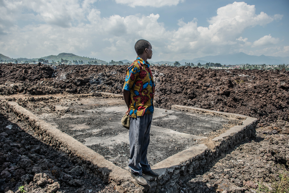 Dieudonné observa as casas em ruínas no seu bairro, Goma, destruídas pela lava na sequência da erupção do vulcão Nyiragongo, a 22 de maio. 
Goma, Kivu do Norte, República Democrática do Congo. Junho de 2021
© Moses Sawasawa