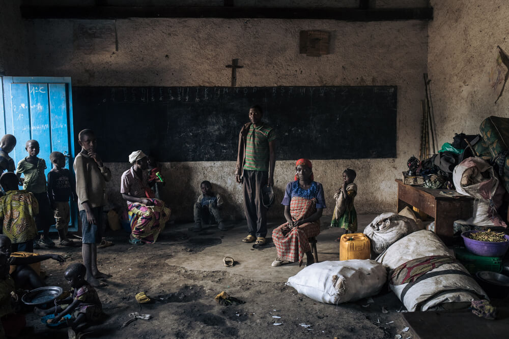 Deslocados, incluindo crianças, abrigados em sala de aula de escola primária em Kivu do Norte, RDC.
