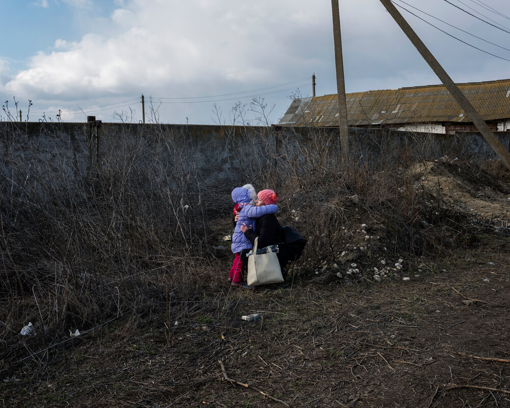 Uma mãe tranquiliza a filha, afastadas de um grupo de pessoas que também esperam para embarcar num autocarro em Palanca, uma área fronteiriça na Moldávia, a três quilómetros de distância da Ucrânia.
