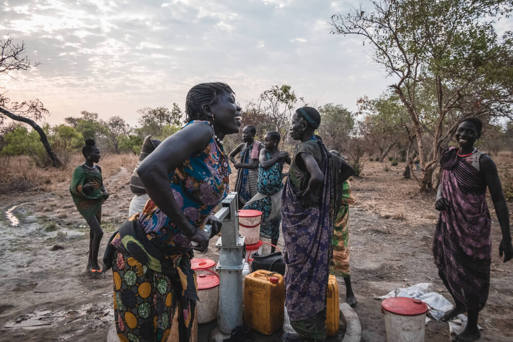 O acesso a água potável é sinónimo de saúde. Nesta imagem feliz, Sera James, residente em Akello, uma aldeia no Sudão do Sul, tira água do poço enquanto partilha uma gargalhada com as amigas.