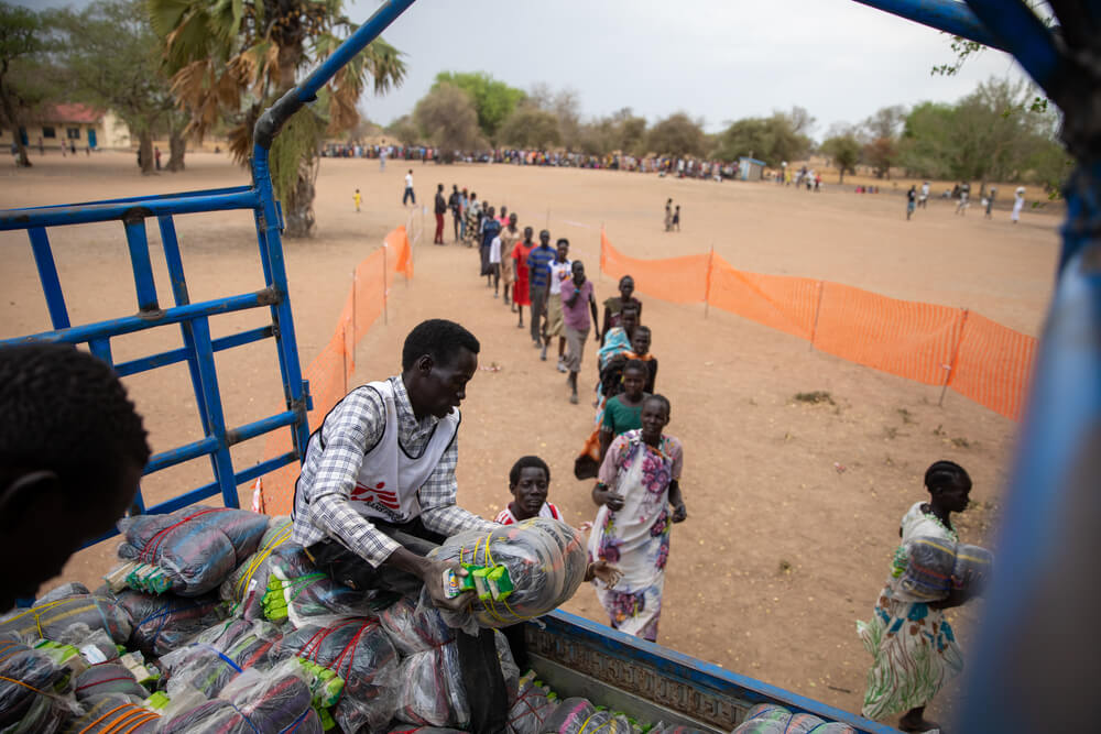Os profissionais de logística da MSF distribuem mantas e bidões no campo para pessoas deslocadas de Nyin Deng Ayuel, no condado de Twic, Sudão do Sul. Depois de fugirem da violência em Agok, milhares de pessoas ficaram sem condições básicas para sobreviver.