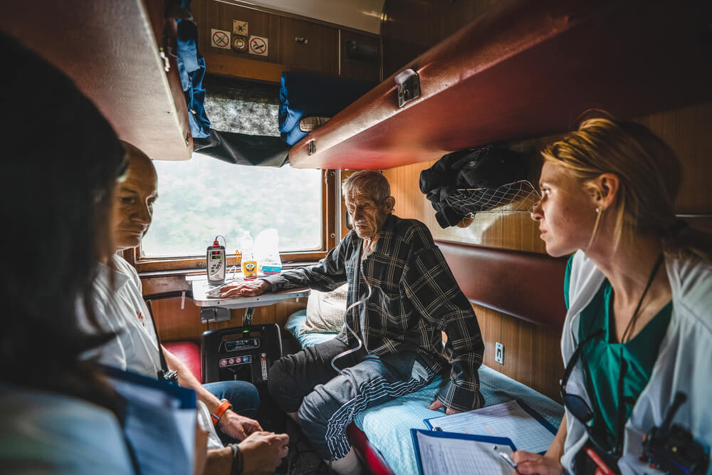 Profissionais da MSF a bordo do comboio medicalizado na Ucrânia analisam o estado de saúde de um paciente ferido de guerra, durante a viagem de Pokrovsk até Lviv, que demora aproximadamente 20 horas. Desde 31 de março, a MSF transportou já mais