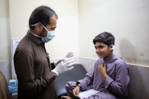 O técnico médico da MSF Muhammad Feroze Shah presta atendimento a Sudais, de 10 anos, no centro de tratamento da leishmaniose cutânea no Hospital Memorial Naseerullah Khan Baber, em Peshawar, no Paquistão. 