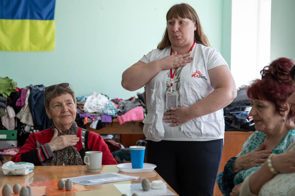 Nataliia Seleznova, promotora de saúde da MSF, realiza um exercício de respiração com pessoas de Kherson que estão deslocadas internamente em Vinnytsia.