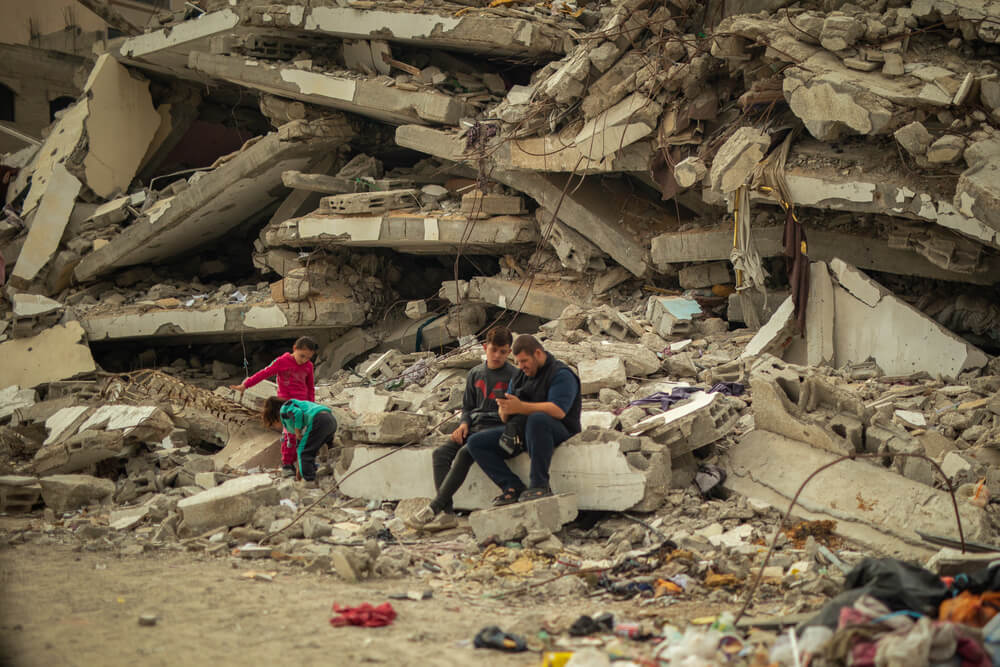 Em Al Saraya, em Gaza, as pessoas estão sentadas sobre escombros da casa destruída, com uma tenda montada em frente aos destroços. MSF