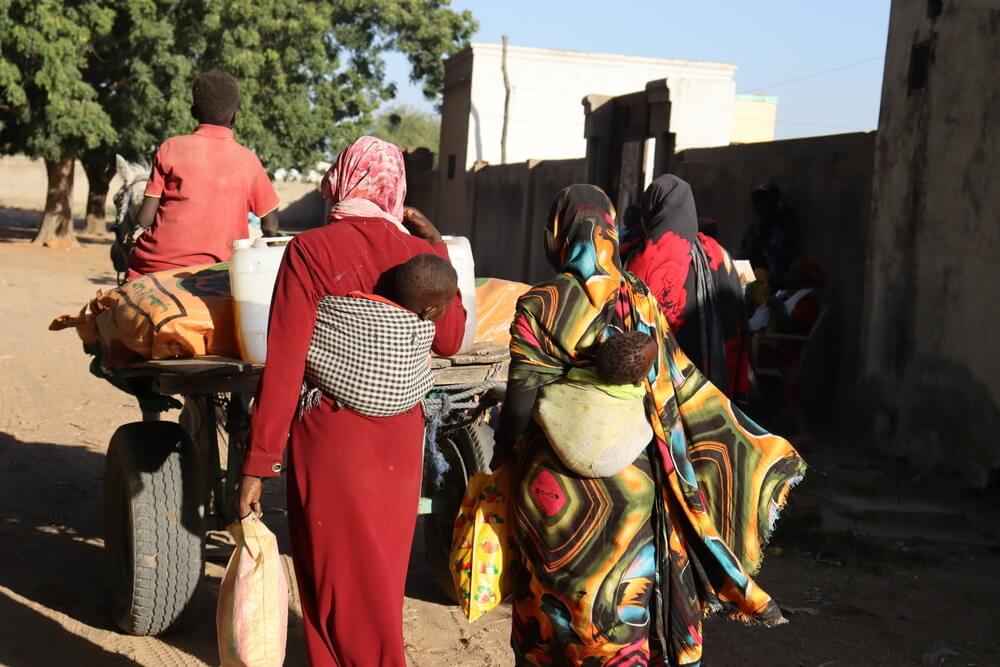 Distribuição de alimentos no Darfur do Sul. Duas mulheres, depois de receberem os seus cabazes de alimentos, iniciam a viagem de regresso a casa numa carroça.