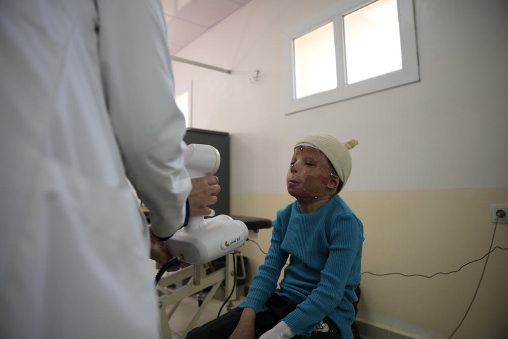Um membro da equipa de impressão 3D da MSF faz uma digitalização facial de um jovem paciente com queimaduras faciais graves.