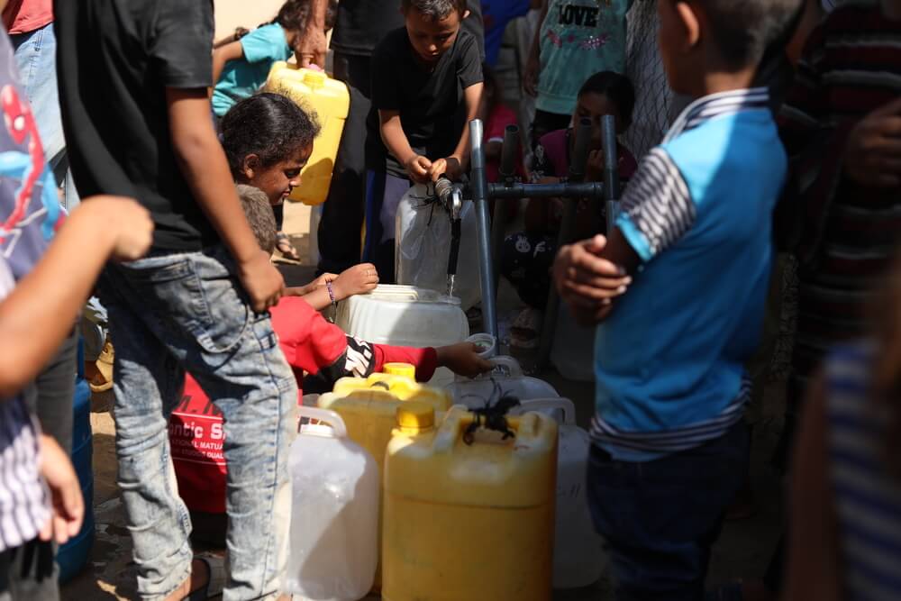 Pessoas tentam obter água em um ponto de distribuição de água da Médicos Sem Fronteiras que funciona ao lado do nosso Centro de Cuidados de Saúde Primários em Mawasi, na Faixa de Gaza.
