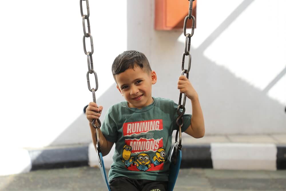 Omar senta-se no parque infantil do hospital de cirurgia reconstrutiva em Amã, Jordânia. Omar ficou ferido num ataque israelita em Gaza.