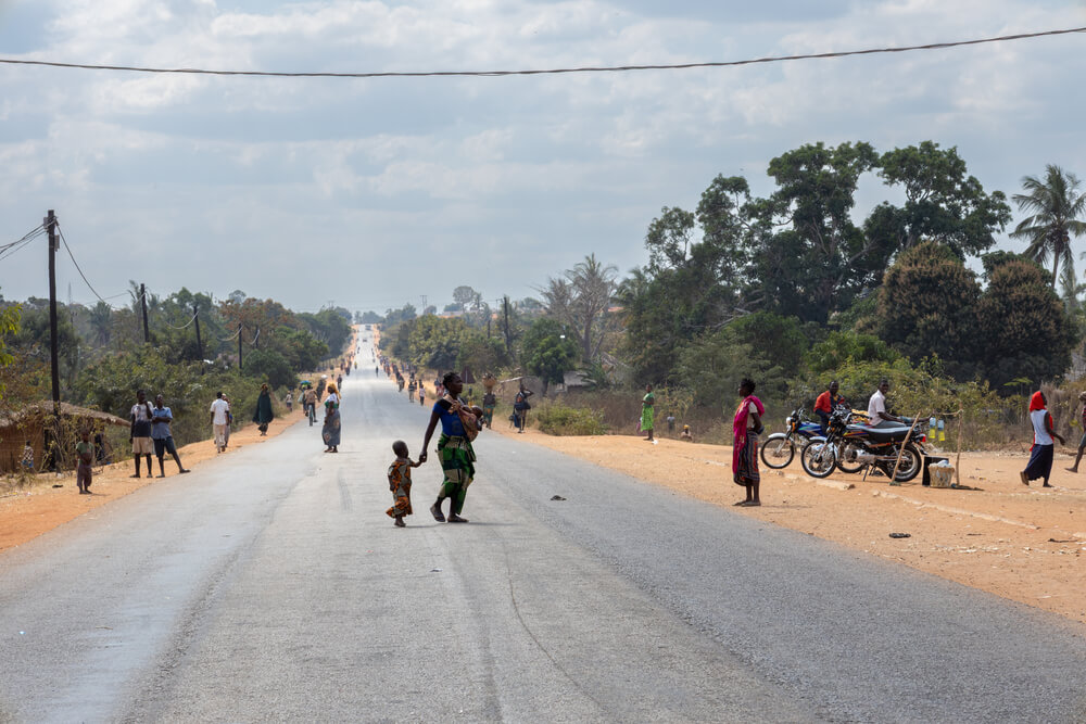 Pessoas caminham ao longo de uma estrada na província de Cabo Delgado, que tem sido afetada tanto por conflitos como por desastres naturais. Estes acontecimentos forçam frequentemente as comunidades a deslocações repetidas e a viverem com o trauma contínuo da perda das casas e meios de subsistência. Cabo Delgado, Moçambique, agosto de 2025.