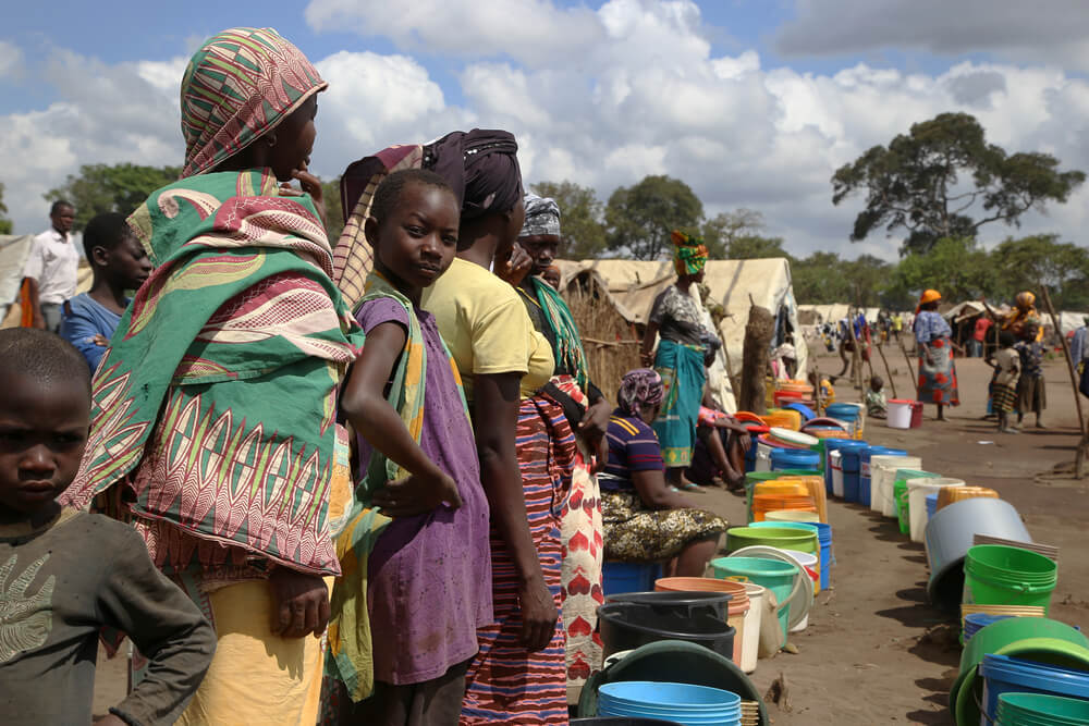 Mulheres e raparigas fazem fila num ponto de abastecimento de água em Eduardo Mondlane, um local de instalação para pessoas deslocadas na vila de Mueda, província de Cabo Delgado, Norte de Moçambique.