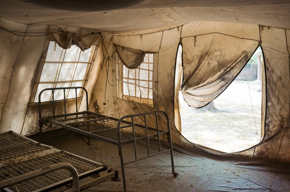 No interior do complexo do Hospital Madre Teresa, uma tenda de lona vazia, com estruturas de camas enferrujadas, é utilizada como enfermaria de apoio quando o número de pacientes aumenta. Turalei, Condado de Twic, Sudão do Sul.