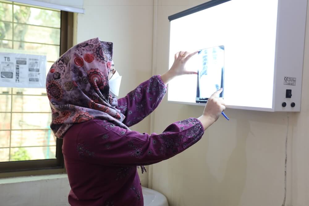 A médica da MSF, Hafsa Fatima, analisa a radiografia de um paciente durante o atendimento pediátrico na clínica da MSF em Gujranwala, Punjab, no Paquistão.