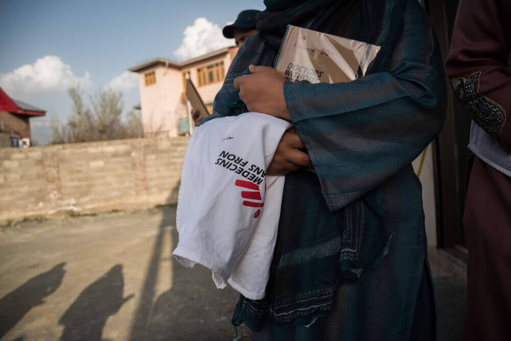 Uma trabalhadora de saúde mental comunitária segura o colete e um calendário da MSF. Jammu e Caxemira, Índia.