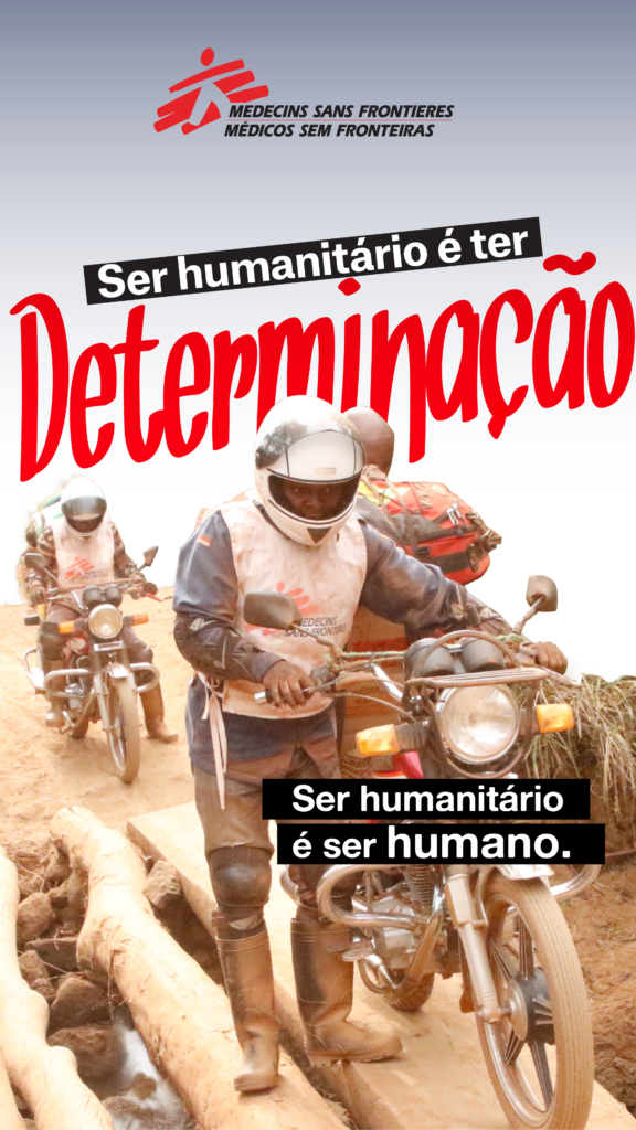 Imagem da campanha Ser Humanitário é Ser Humano com a palavra “dedicação” sobre a fotografia de profissionais da MSF a atravessar uma estrada de terra em motas.