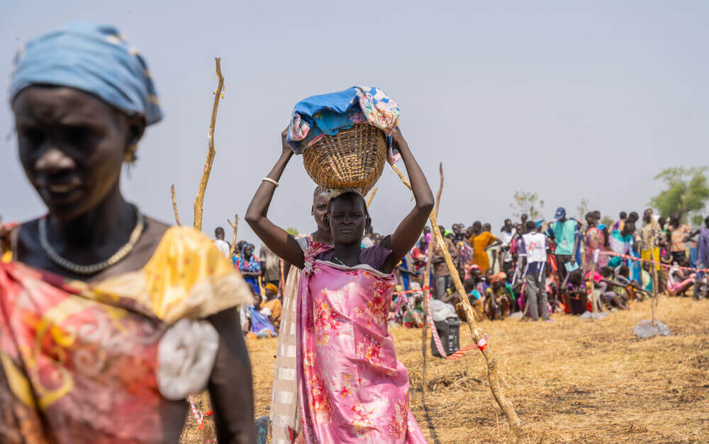 Uma mulher transporta o bebé num cesto enquanto aguarda receber bens de primeira necessidade durante uma distribuição em Chuil, no estado de Jonglei, Sudão do Sul. 