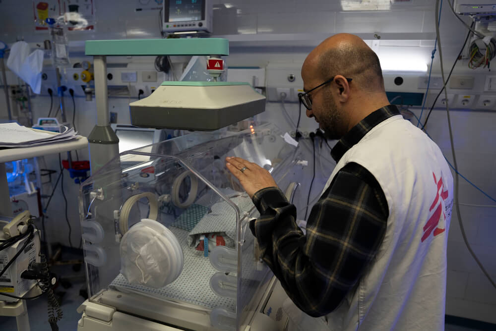 Um membro da equipa do Hospital Al-Helou, na cidade de Gaza, examina um recém-nascido com baixo peso que está internado numa incubadora.