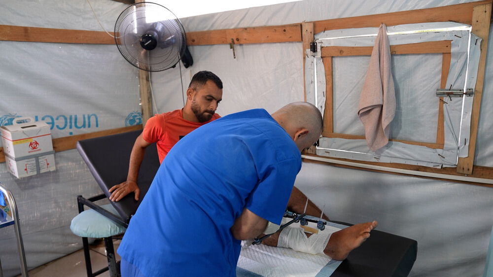 Um membro da equipa de MSF examina a lesão de Saad Hussein, que tem de viver com um fixador externo depois de ter ficado ferido em 2025 durante uma distribuição de alimentos organizada pela GHF.