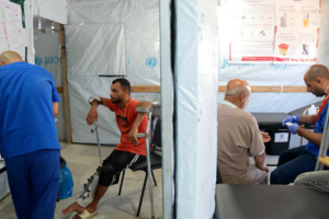 Um membro da equipa de MSF examina a lesão de Saad Hussein, que tem de viver com um fixador externo depois de ter ficado ferido em 2025 durante uma distribuição de alimentos organizada pela GHF.