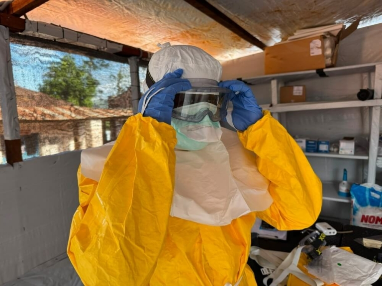 Um membro da equipa de MSF ajusta os óculos de proteção dentro da área de resposta ao Ébola no Hospital Geral de Referência de Mongbwalu, em Ituri, na República Democrática do Congo. Anna SCHÖNHOFER/MSF