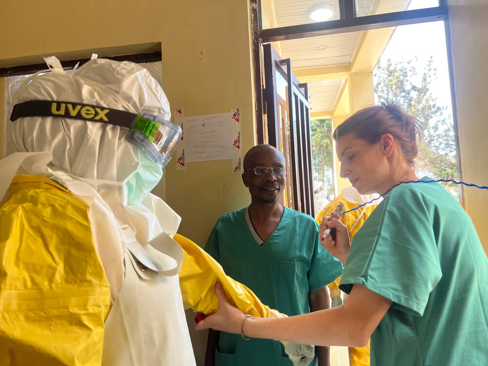 Uma enfermeira da MSF escreve os nomes dos enfermeiros no EPI para garantir que estejam identificáveis quando entrarem nos quartos dos pacientes com Ébola em Bukavu, no Kivu Sul. 