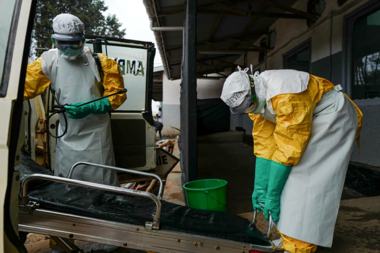 Dois profissionais higienizam uma ambulância que transportou um caso suspeito de Ébola no centro de isolamento de Butembo, na RDC.