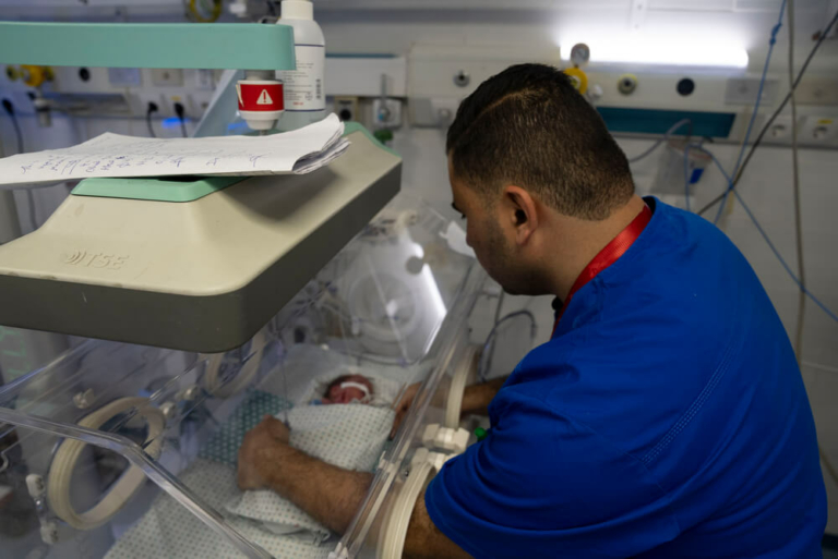 Um trabalhador do Hospital Al-Helou, na cidade de Gaza, examina um recém-nascido com baixo peso que está numa incubadora.