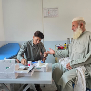Na unidade de cuidados de saúde primários da MSF no vale de Tirah, Khyber Pakhtunkhwa, um profissional de saúde verifica o nível de açúcar no sangue de um paciente — um exame de rotina que ajuda a prevenir complicações da diabetes em uma região remota.