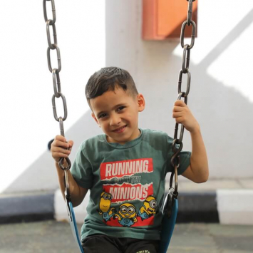 Omar senta-se no parque infantil do hospital de cirurgia reconstrutiva em Amã, Jordânia. Omar ficou ferido num ataque israelita em Gaza.