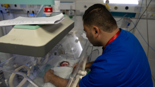 Um trabalhador do Hospital Al-Helou, na cidade de Gaza, examina um recém-nascido com baixo peso que está numa incubadora.