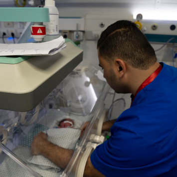 Um trabalhador do Hospital Al-Helou, na cidade de Gaza, examina um recém-nascido com baixo peso que está numa incubadora.