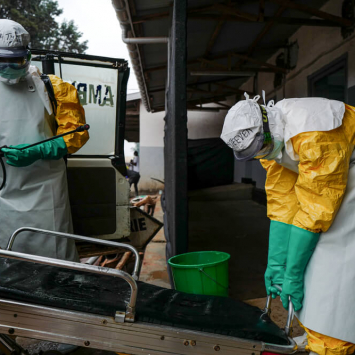 Dois profissionais higienizam uma ambulância que transportou um caso suspeito de Ébola no centro de isolamento de Butembo, na RDC.