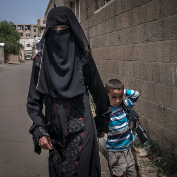 Uma mulher e seu filho perto do hospital de MSF em Sanaa. O menino está carregando uma arma de brinquedo, imitando o comportamento que observa ao seu redor.